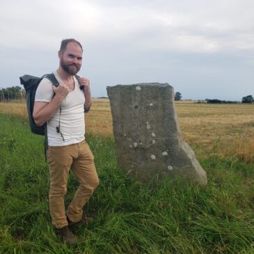 Galen looks happier than a clam in mud at high tide, though he is in fact hiking near a carven rock with a backpace.