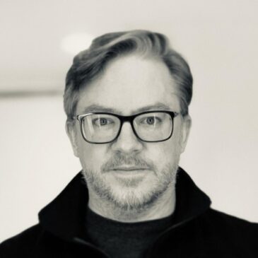 This black and white photo of James Tauber does not dim the spark in his eyes. His glasses do not dim it. We are not distracted by his casual black attire. It's the eyes. They are mirrors. Do you need a challenge? Do you need to hear that you can do something you've never tried? Look into those mirrors. Really. You'll be able to pull your gaze away any time now.