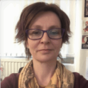 Sara Brown's windswept brown hair reminds us that she lives in the wilds of Wales. She's got very serious horn-rimmed glasses and a lovely scarf, the very picture of a serious professor except that she's fighting back a grin and a dozen sharp puns.