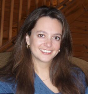 Dr. Amy H. Sturgis is smiling at us with open, friendly eyes and a broad grin. She is waiting in a room with wooden walls and a wooden staircase, making us think of curling up in a cabin at story time to listen to her read beside the fire.