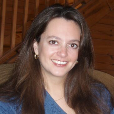 Dr. Amy H. Sturgis is smiling at us with open, friendly eyes and a broad grin. She is waiting in a room with wooden walls and a wooden staircase, making us think of curling up in a cabin at story time to listen to her read beside the fire.